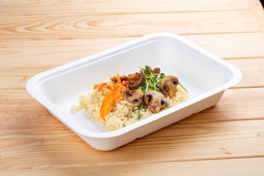 Mantarlı bulgur. Sağlıklı beslenme. Paket yemek. Çevre ambalajı. Ahşap bir arka planda.