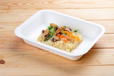 Mantarlı bulgur. Sağlıklı beslenme. Paket yemek. Çevre ambalajı. Ahşap bir arka planda.