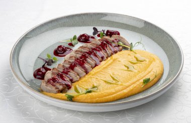 Ördek göğsü, balkabağı püresi, kiraz sosu ve fıstık. İzole edilmiş resim