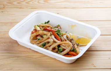 Kalamar makarnası. Sağlıklı yiyecekler. Paket yemek. Ahşap bir arka planda.