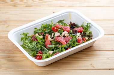 Greyfurt ve roka ile sulu salata. Sağlıklı beslenme. Paket yemek. Ahşap bir arka planda.