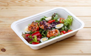 Hafif tuzlu somon ve dolmalık biberli salata. Sağlıklı yiyecekler. Paket yemek. Ahşap bir arka planda.