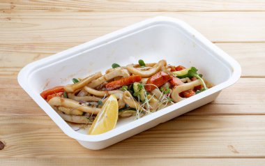 Kalamar makarnası. Sağlıklı yiyecekler. Paket yemek. Ahşap bir arka planda.