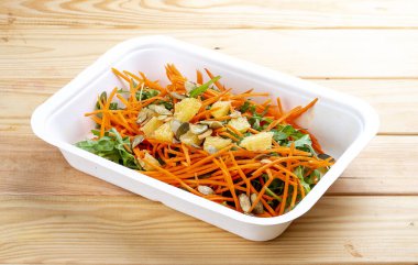 Portakallı havuç salatası. Sağlıklı yiyecekler. Paket yemek. Ahşap bir arka planda.
