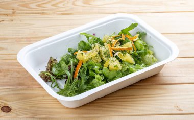 Roka salatası, havuç ve portakal. Vejetaryen yemeği. Paket yemek. Ahşap bir arka planda.