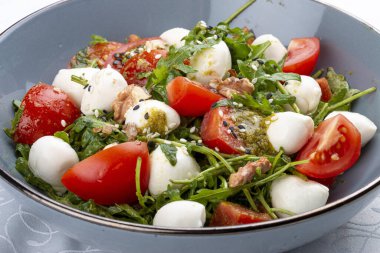 Caprese salatası, kiraz domatesleri, mozzarella, roka ve pesto sosu. İzole edilmiş resim