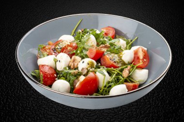Caprese salatası, kiraz domatesleri, mozzarella, roka ve pesto sosu. İzole edilmiş resim
