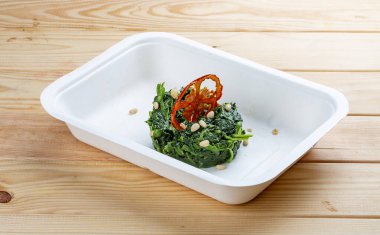 Çam fıstıklı haşlanmış ıspanak. Sağlıklı yiyecekler. Paket yemek. Ahşap bir arka planda.