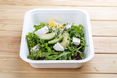 Salata karışımı (sebze, avokado ve tofu). Sağlıklı yiyecekler. Paket yemek. Ahşap bir arka planda.