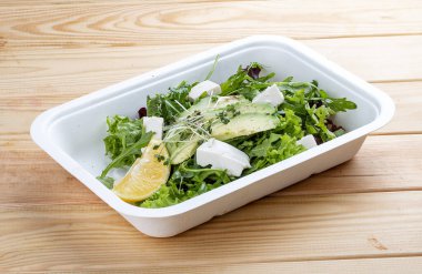 Salata karışımı (sebze, avokado ve tofu). Sağlıklı yiyecekler. Paket yemek. Ahşap bir arka planda.