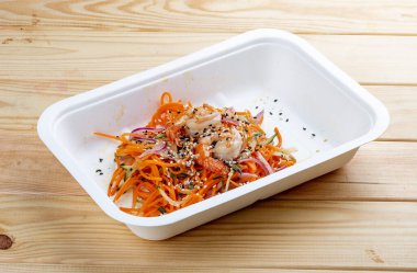 Karides, taze sebze ve baharatlı havuçlu Kore usulü salata. Sağlıklı yiyecekler. Paket yemek. Ahşap bir arka planda.