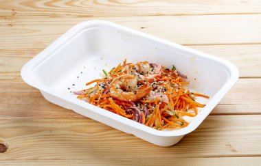 Karides, taze sebze ve baharatlı havuçlu Kore usulü salata. Sağlıklı yiyecekler. Paket yemek. Ahşap bir arka planda.