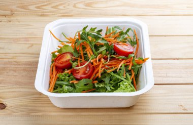 Salata karışımı (sebze, havuç ve vişneli domates). Sağlıklı yiyecekler. Paket yemek. Ahşap bir arka planda.
