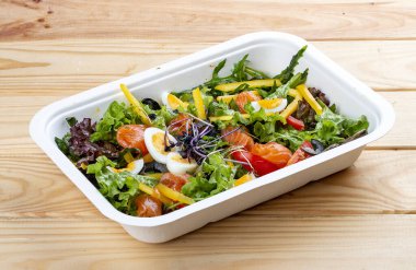 Hafif tuzlu somon ve dolmalık biberli salata. Sağlıklı yiyecekler. Paket yemek. Ahşap bir arka planda.