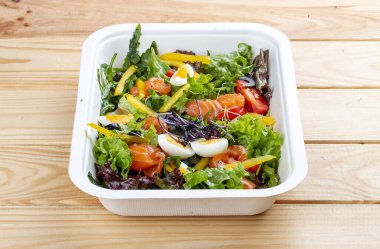 Hafif tuzlu somon ve dolmalık biberli salata. Sağlıklı yiyecekler. Paket yemek. Ahşap bir arka planda.