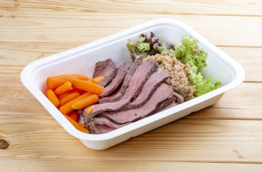 Sulu havuçlu dana sosu. Sağlıklı beslenme. Paket yemek. Çevre ambalajı. Ahşap bir arka planda.