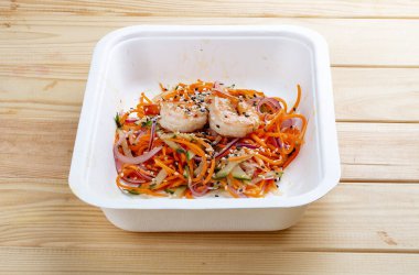 Karides, taze sebze ve baharatlı havuçlu Kore usulü salata. Sağlıklı yiyecekler. Paket yemek. Ahşap bir arka planda.