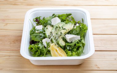 Salata karışımı (sebze, avokado ve tofu). Sağlıklı yiyecekler. Paket yemek. Ahşap bir arka planda.