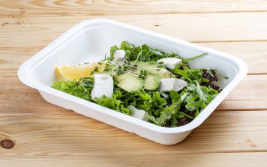 Salata karışımı (sebze, avokado ve tofu). Sağlıklı yiyecekler. Paket yemek. Ahşap bir arka planda.