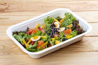 Hafif tuzlu somon ve dolmalık biberli salata. Sağlıklı yiyecekler. Paket yemek. Ahşap bir arka planda.