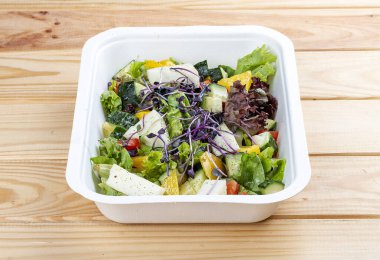 Camembert peynirli Fransız salatası. Sağlıklı yiyecekler. Paket yemek. Ahşap bir arka planda.