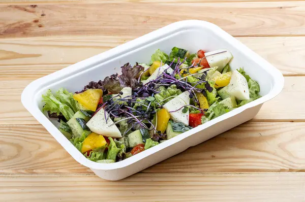 Camembert peynirli Fransız salatası. Sağlıklı yiyecekler. Paket yemek. Ahşap bir arka planda.