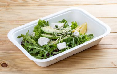 Salata karışımı (sebze, avokado ve tofu). Sağlıklı yiyecekler. Paket yemek. Ahşap bir arka planda.