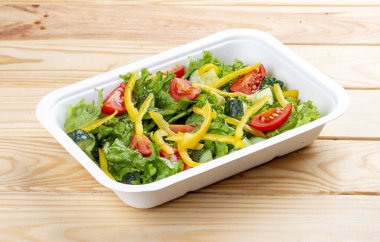 Salatalı salata, domates ve tatlı biber. Sağlıklı yiyecekler. Paket yemek. Ahşap bir arka planda.