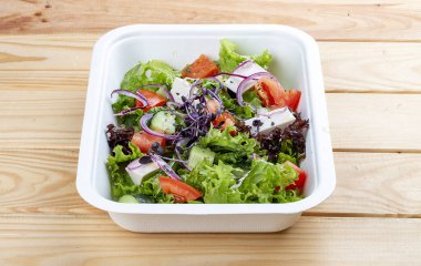 Peynirli Yunan salatası. Sağlıklı beslenme. Paket yemek. Ahşap bir arka planda.