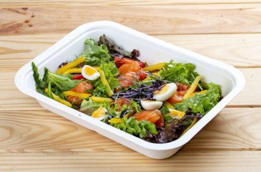 Hafif tuzlu somon ve dolmalık biberli salata. Sağlıklı yiyecekler. Paket yemek. Ahşap bir arka planda.