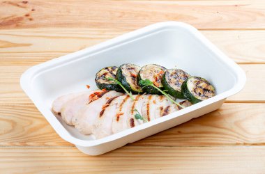 Kabaklı ızgara tavuk göğsü. Sağlıklı beslenme. Paket yemek. Ahşap bir arka planda.