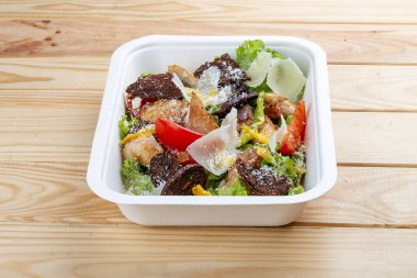 Tavuklu Fitness Sezar salatası. Sağlıklı yiyecekler. Paket yemek. Ahşap bir arka planda.