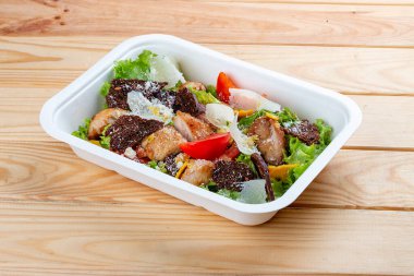 Tavuklu Fitness Sezar salatası. Sağlıklı yiyecekler. Paket yemek. Ahşap bir arka planda.