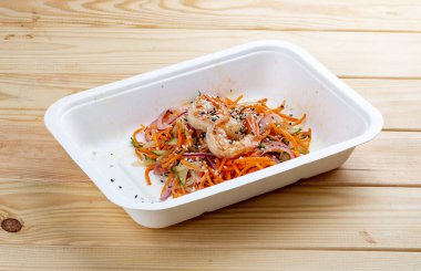 Karides, taze sebze ve baharatlı havuçlu Kore usulü salata. Sağlıklı yiyecekler. Paket yemek. Ahşap bir arka planda.