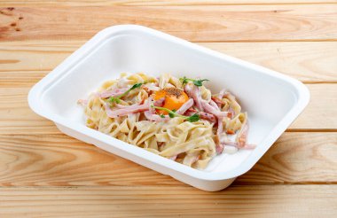 Carbonara makarnası. Sağlıklı yiyecekler. Paket yemek. Ahşap bir arka planda.