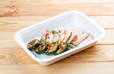 Kabaklı ızgara tavuk göğsü. Sağlıklı beslenme. Paket yemek. Ahşap bir arka planda.