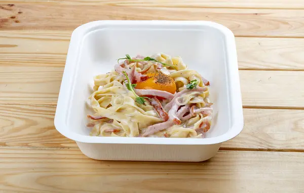 Carbonara pasta. Healthy food. Takeaway food. On a wooden background.