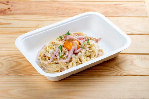 Carbonara pasta. Healthy food. Takeaway food. On a wooden background.