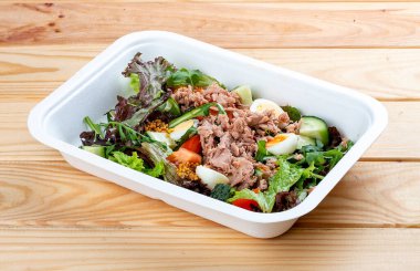 Ton balıklı ve bıldırcın yumurtalı ton balığı salatası. Sağlıklı yiyecekler. Paket yemek. Ahşap bir arka planda.