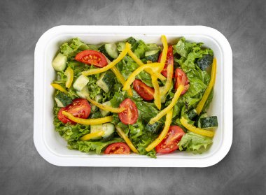 Salatalı salata, domates ve tatlı biber. Sağlıklı yiyecekler. Paket yemek. Üst görünüm, gri arkaplanda.