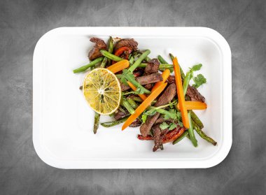 Veal with beans and orange. Healthly food. Takeaway food. Top view, on a gray background. clipart