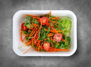 Salata karışımı (sebze, havuç ve vişneli domates). Sağlıklı yiyecekler. Paket yemek. Üst görünüm, gri arkaplanda.