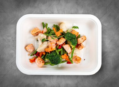 Pişmiş somon ve sebze. Sağlıklı beslenme. Paket yemek. Çevre ambalajı. Üst görünüm, gri arkaplanda.