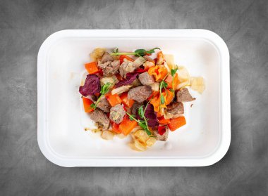 Havuç ve lahana ile pişirilmiş dana filetosu. Sağlıklı beslenme. Paket yemek. Ekolojik ambalaj. Üst görünüm, gri arkaplanda.