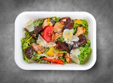 Tavuklu Fitness Sezar salatası. Sağlıklı yiyecekler. Paket yemek. Üst görünüm, gri arkaplanda.