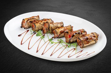 Lezzetli bir etobur lezzet: yumuşak et dumanlı, kömürleşmiş patlıcanı ahenkli bir sarmalla kaplar. Bu gürbüz rulo, kızarmış patlıcanların topraksı zenginliğiyle baharatlı eti birleştirir, dokular ve lezzetlerle nefis bir etkileşim sunar.