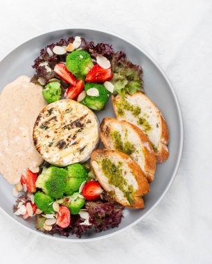 Kaygan Camembert, altın gibi öpülmüş, bahçedeki taze sebzelerin arasına yerleştirilmiş ve kadife soslu.