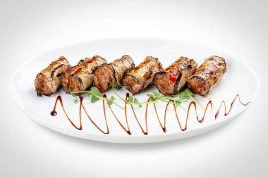 Lezzetli bir etobur lezzet: yumuşak et dumanlı, kömürleşmiş patlıcanı ahenkli bir sarmalla kaplar. Bu gürbüz rulo, kızarmış patlıcanların topraksı zenginliğiyle baharatlı eti birleştirir, dokular ve lezzetlerle nefis bir etkileşim sunar.