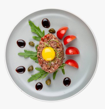 Hassas bir tabak çiğ dana eti, baharatlı ve olgun domatesler ve biberli roka ile eşleştirilmiş..