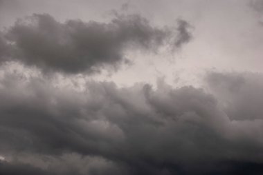 Sky threatening rain and sunshine passing through the clouds. Dark sky and black clouds before rainy, Dramatic black cloud and thunderstorm. The dark sky with heavy clouds converging and a violent storm before the rain.Bad or moody weather sky.